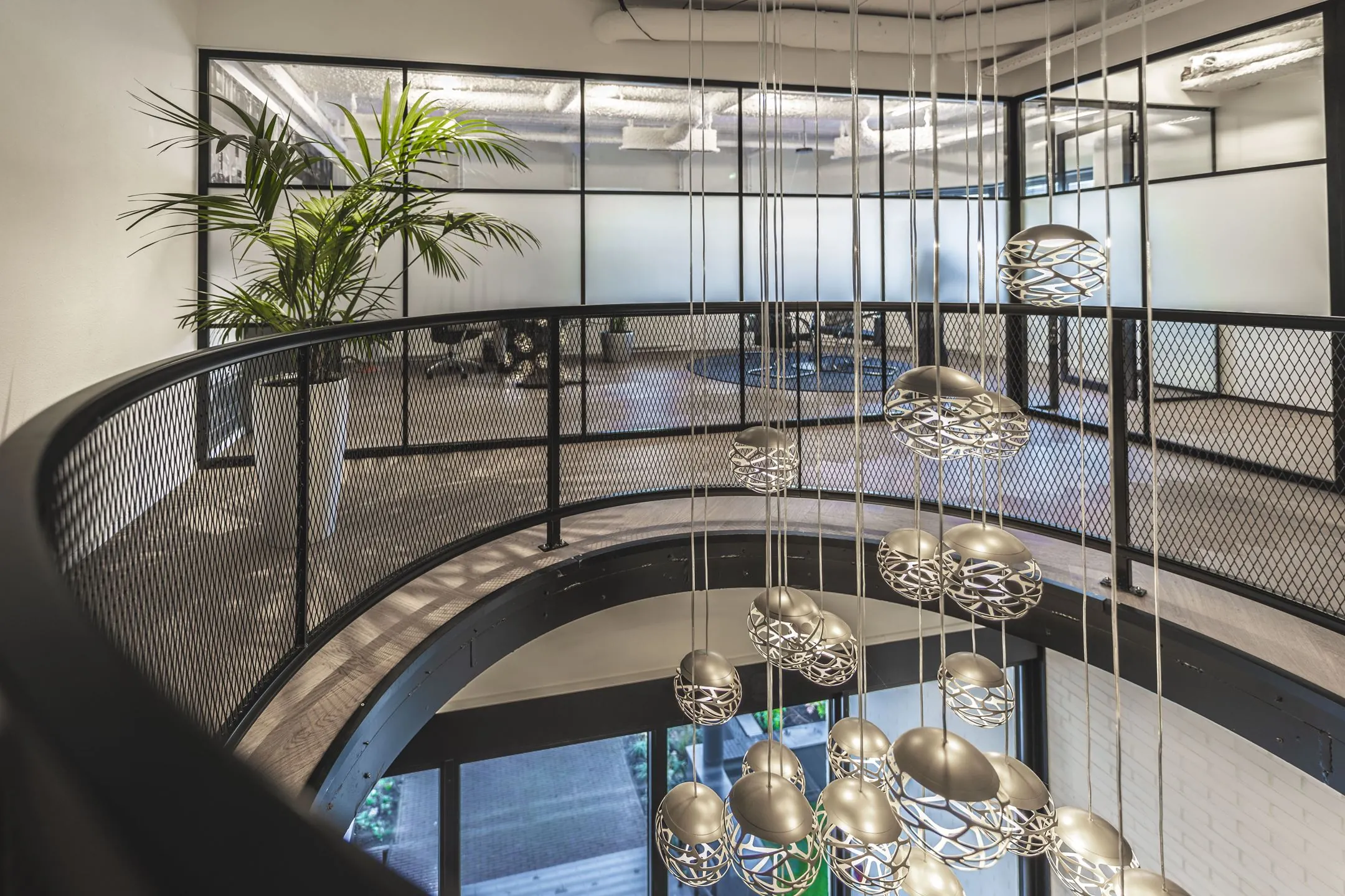 Moderne kantoorruimte aan de Egbert Gorterstraat met glazen wanden, industriële balustrade en hangende designlampen.