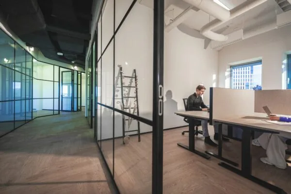 Moderne kantoorruimte aan de Egbert Gorterstraat met glazen wanden, houten vloer en werkplekken met natuurlijke lichtinval.