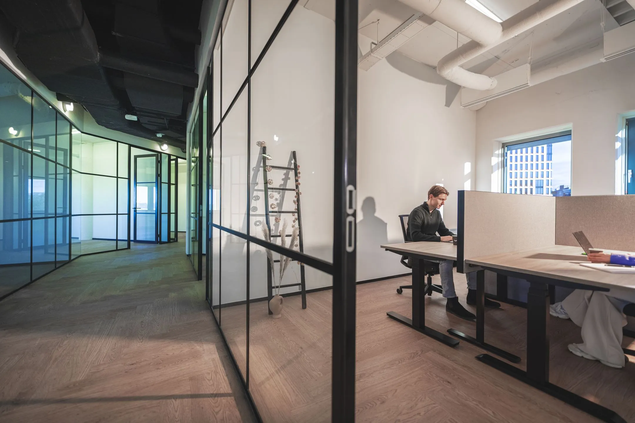 Moderne kantoorruimte aan de Egbert Gorterstraat met glazen wanden, houten vloer en werkplekken met natuurlijke lichtinval.