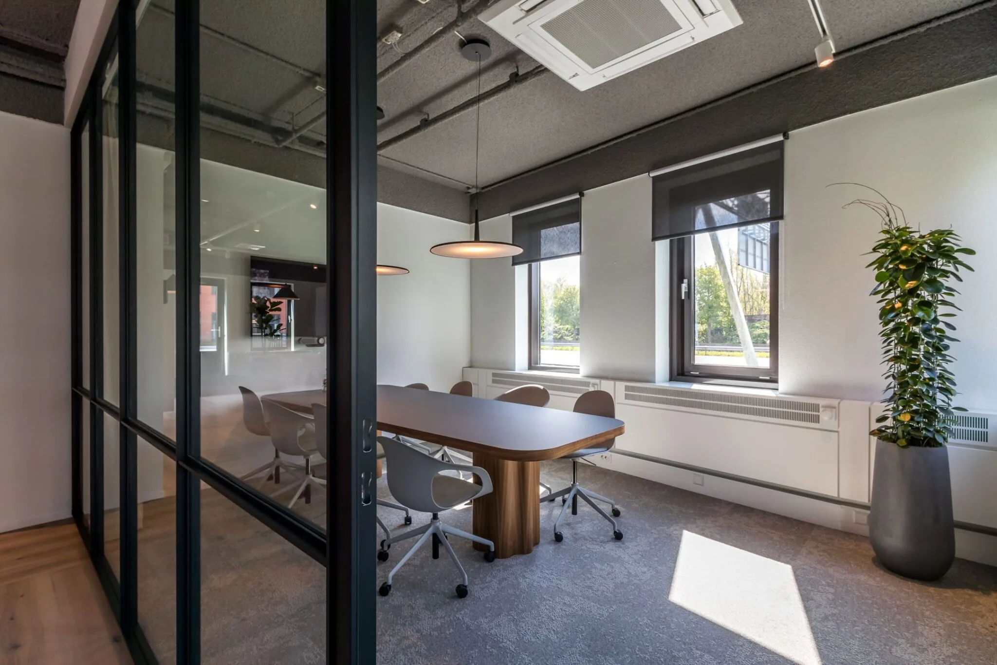 Moderne vergaderruimte aan de Euclideslaan 265 met glazen wand, houten tafel, designstoelen en grote ramen met zonwering.