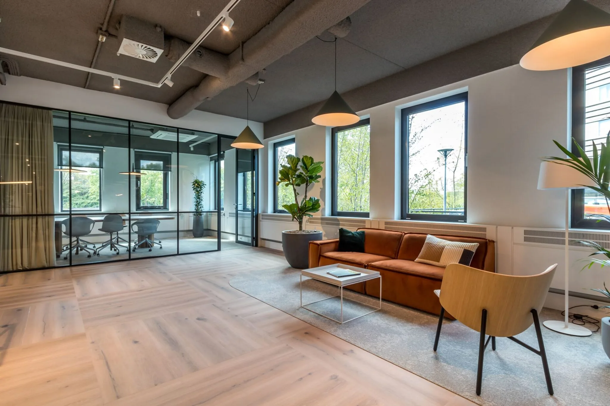 Moderne en sfeervolle wachtruimte met leren bank, houten vloer en glazen vergaderruimte in kantoorpand aan de Euclideslaan 265.