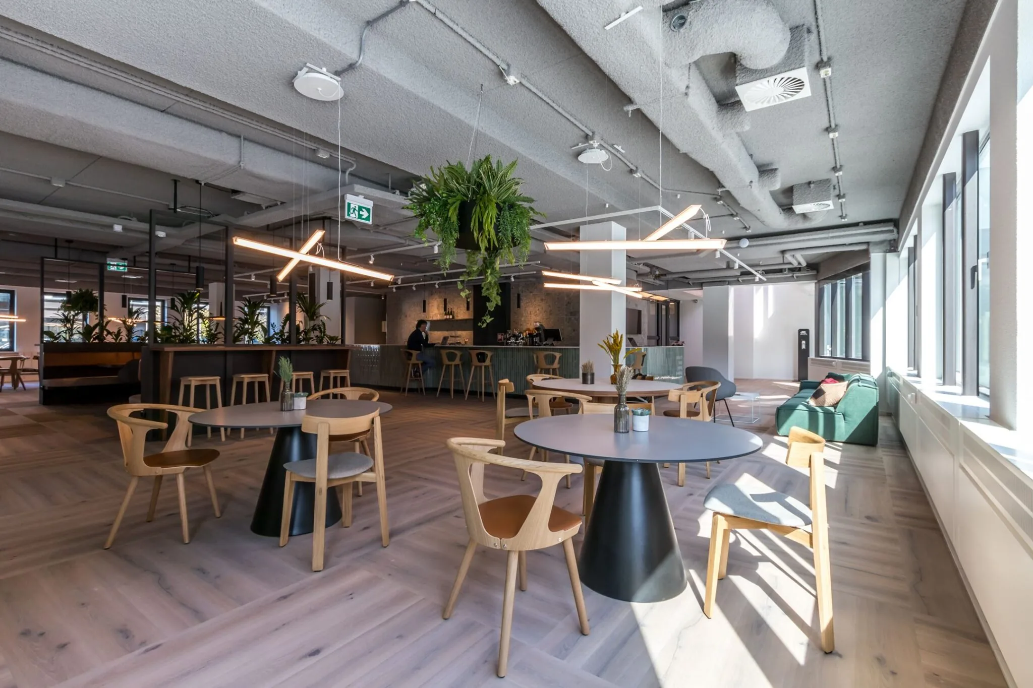 Moderne en lichte kantoorlounge aan de Euclideslaan 265 met zithoeken, een bar, planten en hangverlichting.