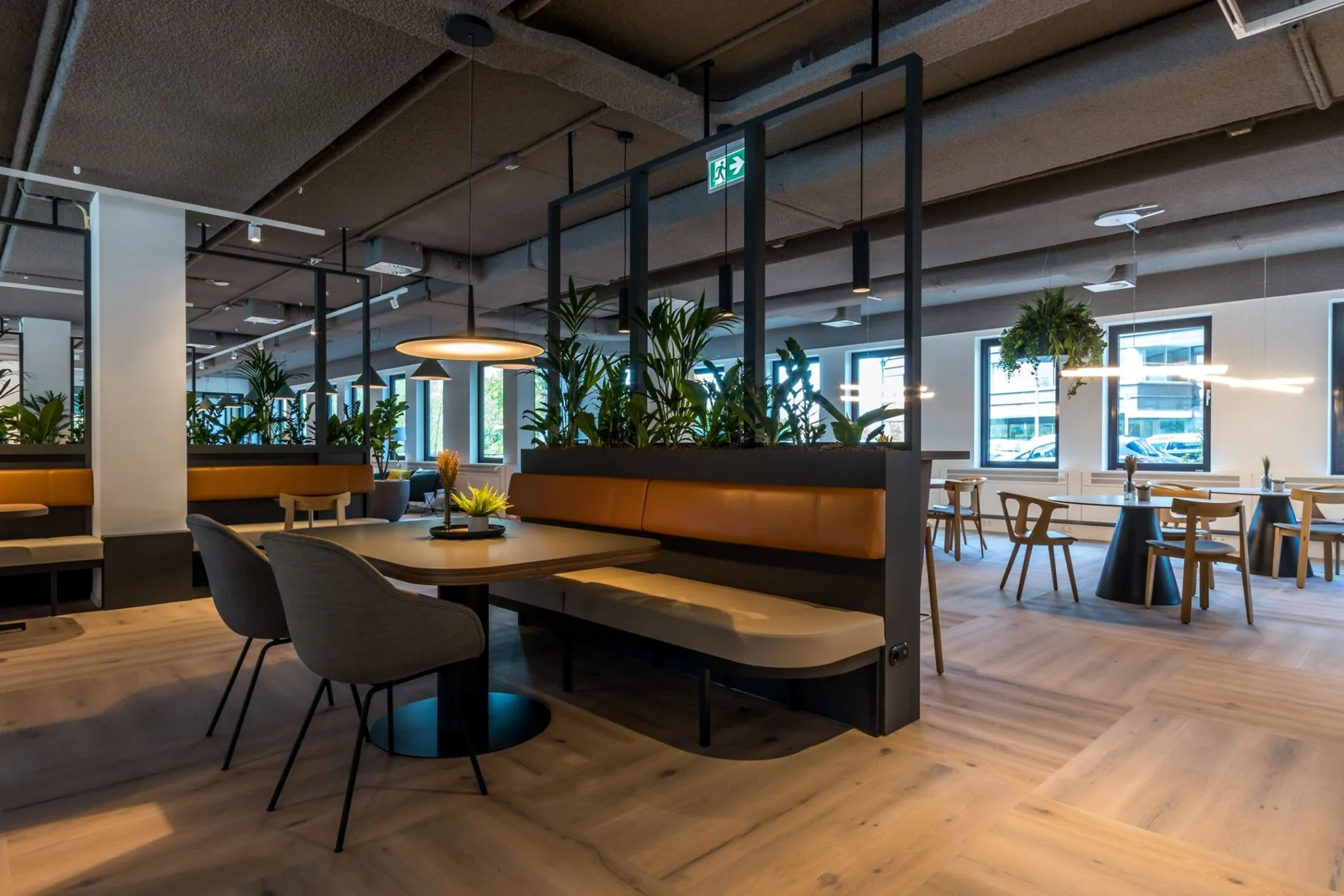 Moderne en sfeervolle kantoorcafetaria in Euclideslaan 265 met houten vloer, designmeubilair en groene planten.