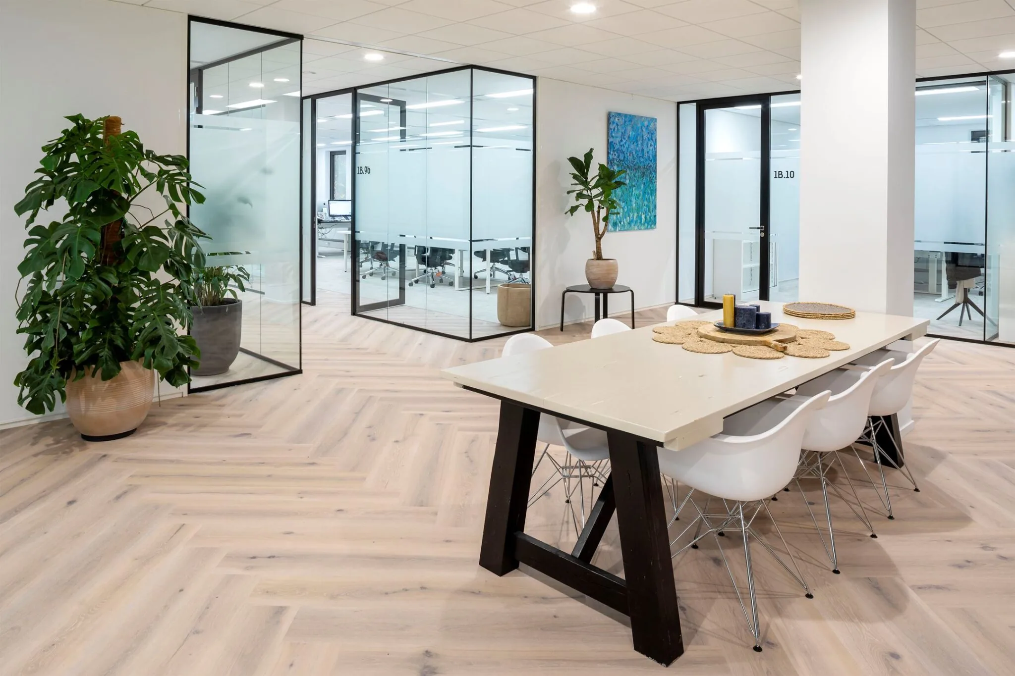 Moderne vergaderruimte aan de Euclideslaan 265 met glazen wanden, houten visgraatvloer, grote tafel en designstoelen.