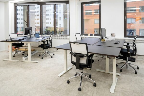 Moderne kantoorruimte aan de Euclideslaan 265 met vier werkplekken, bureaustoelen en grote ramen met uitzicht op kantoorgebouwen.