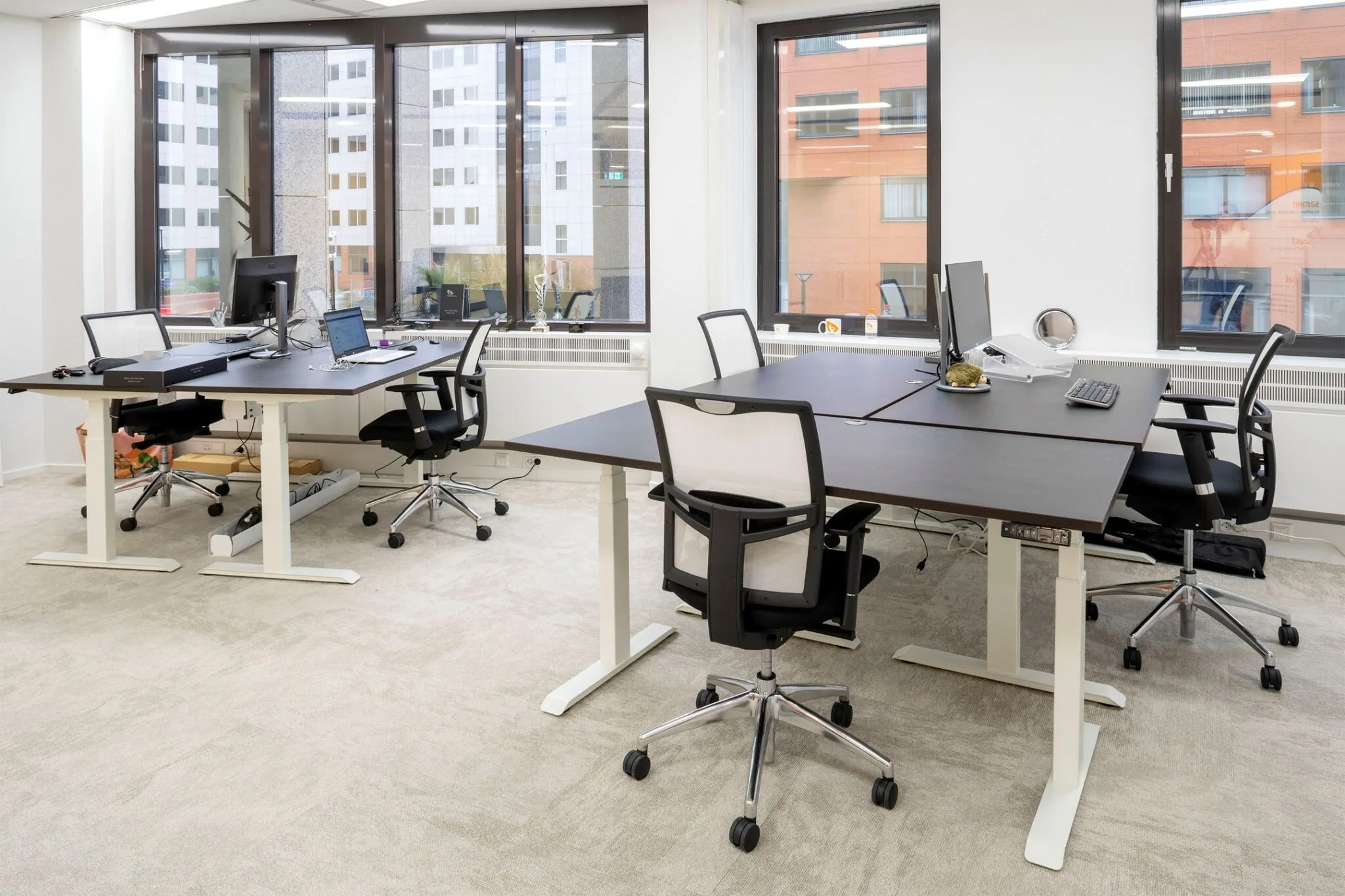 Moderne kantoorruimte aan de Euclideslaan 265 met vier werkplekken, bureaustoelen en grote ramen met uitzicht op kantoorgebouwen.