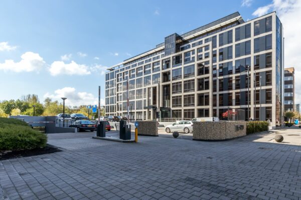 Modern kantoorgebouw aan de Euclideslaan 265 met parkeergarage en auto’s op de voorgrond.