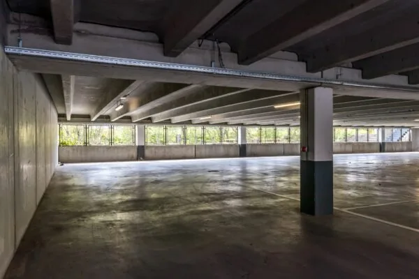Leeg parkeerdek in een betonnen parkeergarage aan de Euclideslaan 265 met grote ramen en zicht op groen.