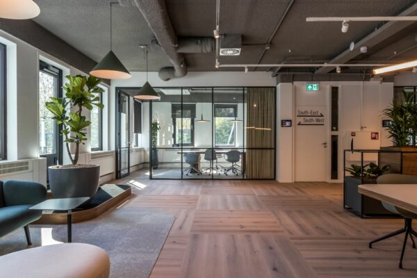 Modern kantoorinterieur aan de Euclideslaan 265 met glazen vergaderruimte, houten vloer en grote planten.