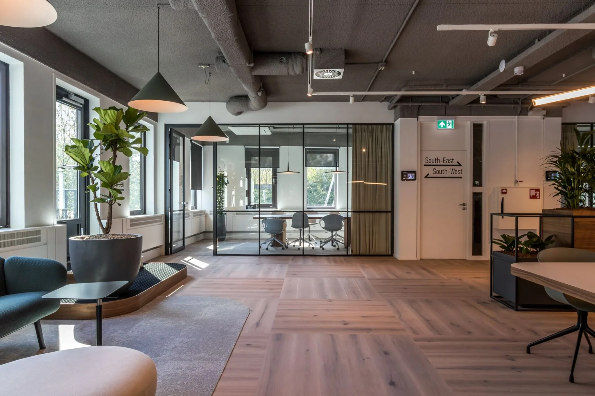 Modern kantoorinterieur aan de Euclideslaan 265 met glazen vergaderruimte, houten vloer en grote planten.