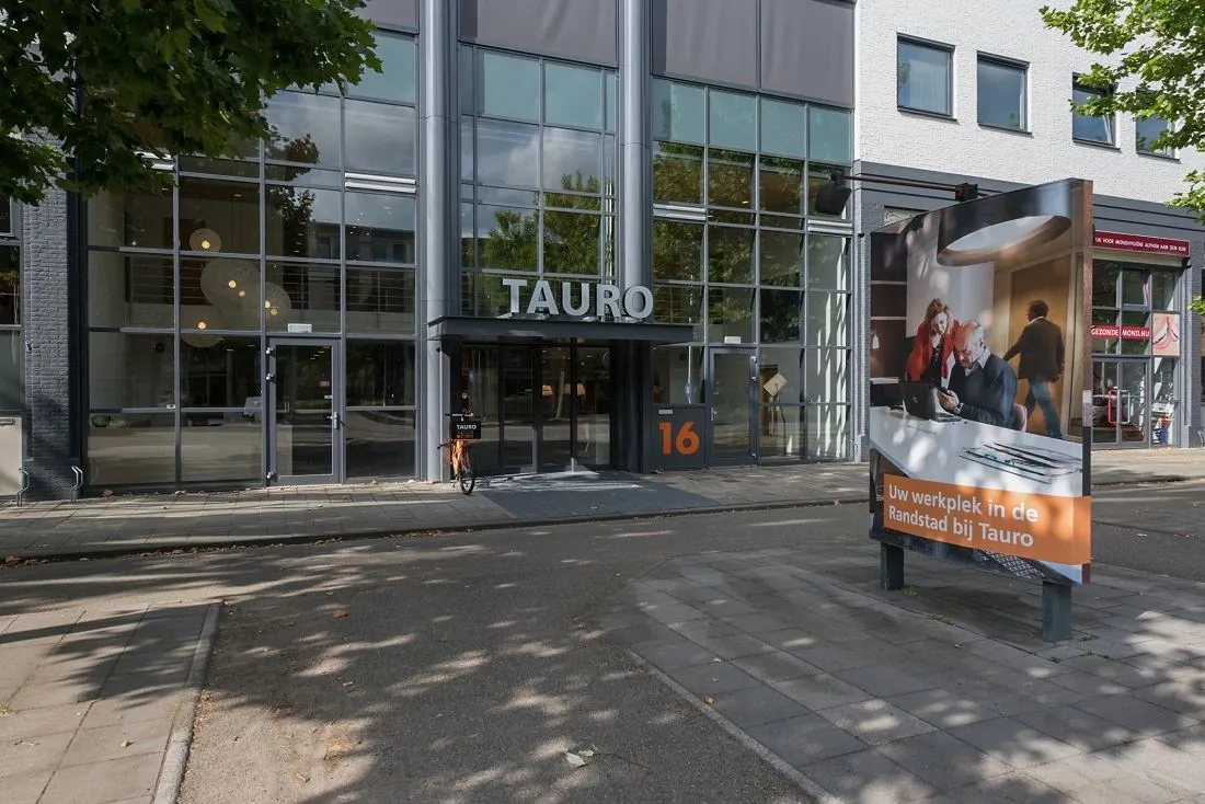 Vooraanzicht van het kantoorgebouw Tauro aan de Europalaan 16 met reclamebord op de stoep.