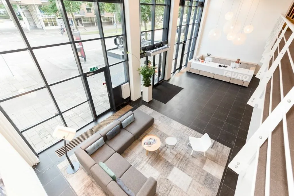 Moderne ontvangsthal van Tauro aan de Europalaan 16 met zithoek, balie en grote raampartijen.