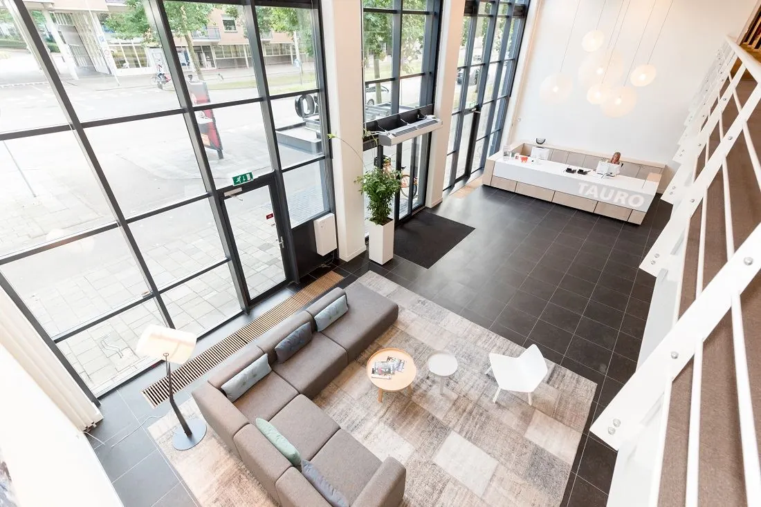 Moderne ontvangsthal van Tauro aan de Europalaan 16 met zithoek, balie en grote raampartijen.