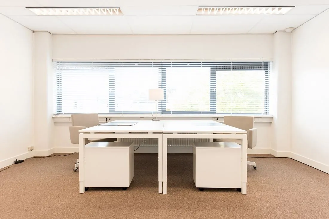 Modern en licht kantoor met twee bureaus, stoelen en een groot raam aan de Europalaan 16.