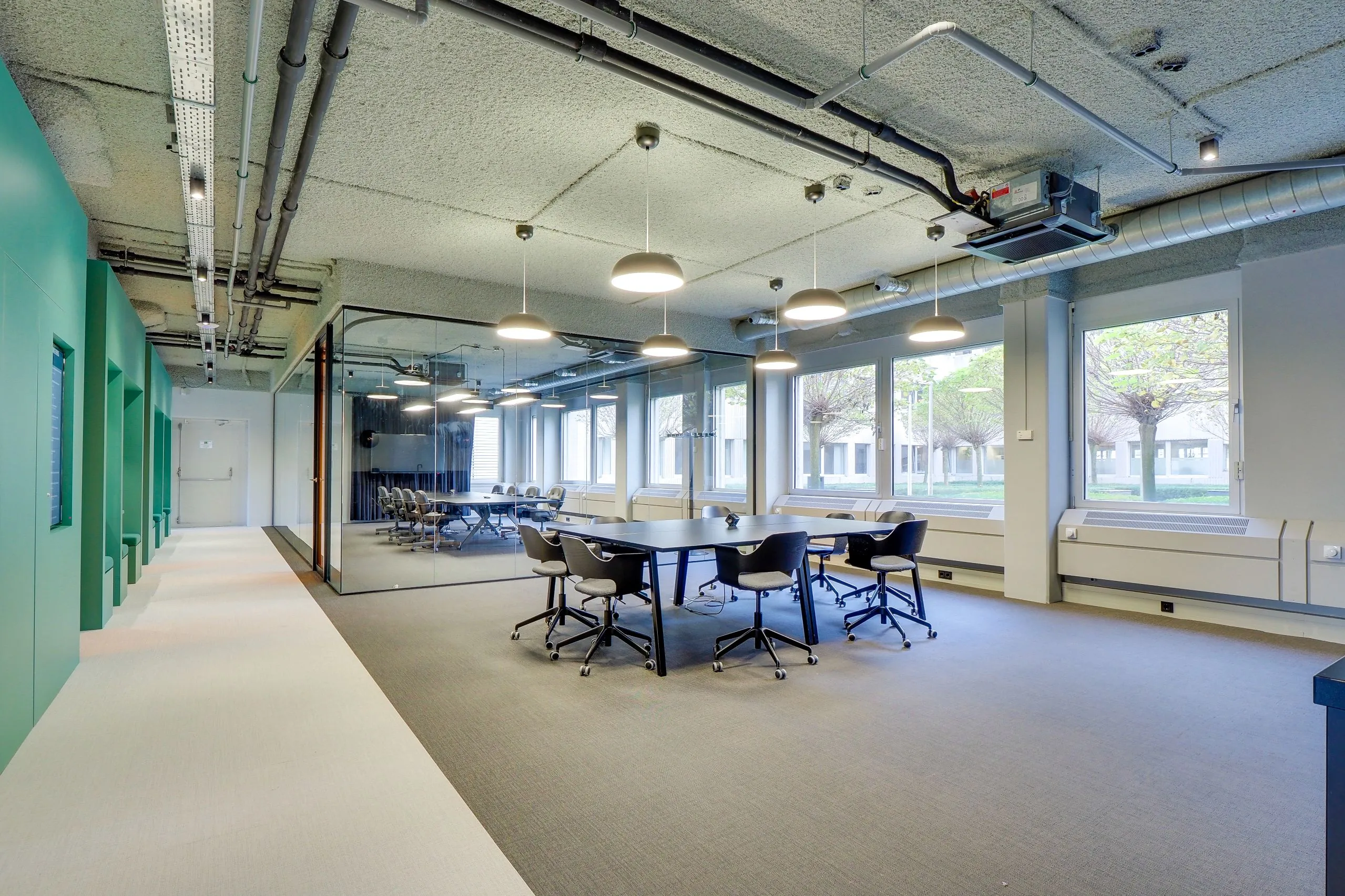 Moderne vergaderruimte bij Europalaan 400 met glazen wanden, zwarte stoelen en grote ramen met uitzicht op bomen.
