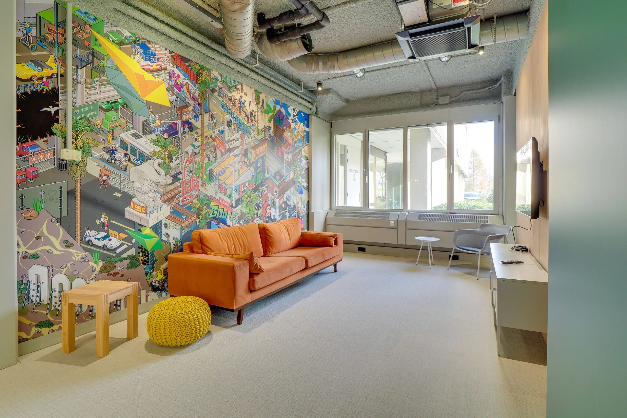 Moderne wachtruimte met een oranje bank, kleurrijke muurschildering in pixel-artstijl en grote ramen in Europalaan 400.