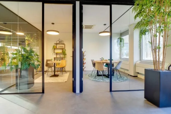 Twee moderne vergaderruimtes met glazen wanden, kleurrijke stoelen en veel groen in kantoor Europalaan 400.