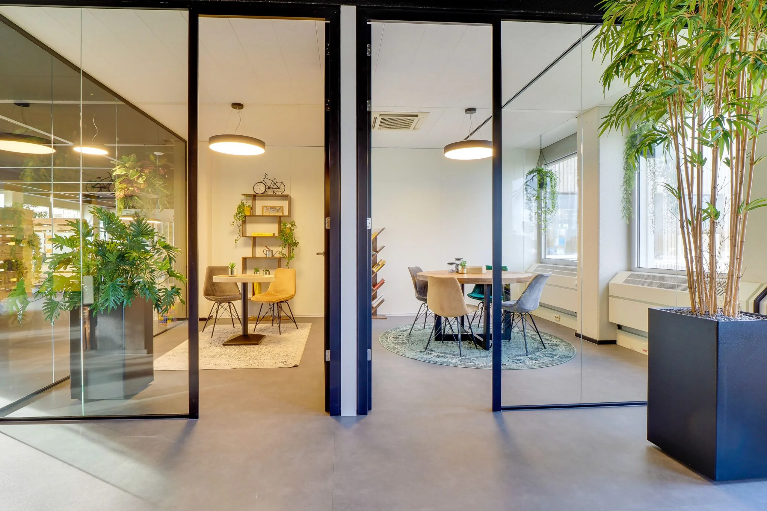 Twee moderne vergaderruimtes met glazen wanden, kleurrijke stoelen en veel groen in kantoor Europalaan 400.