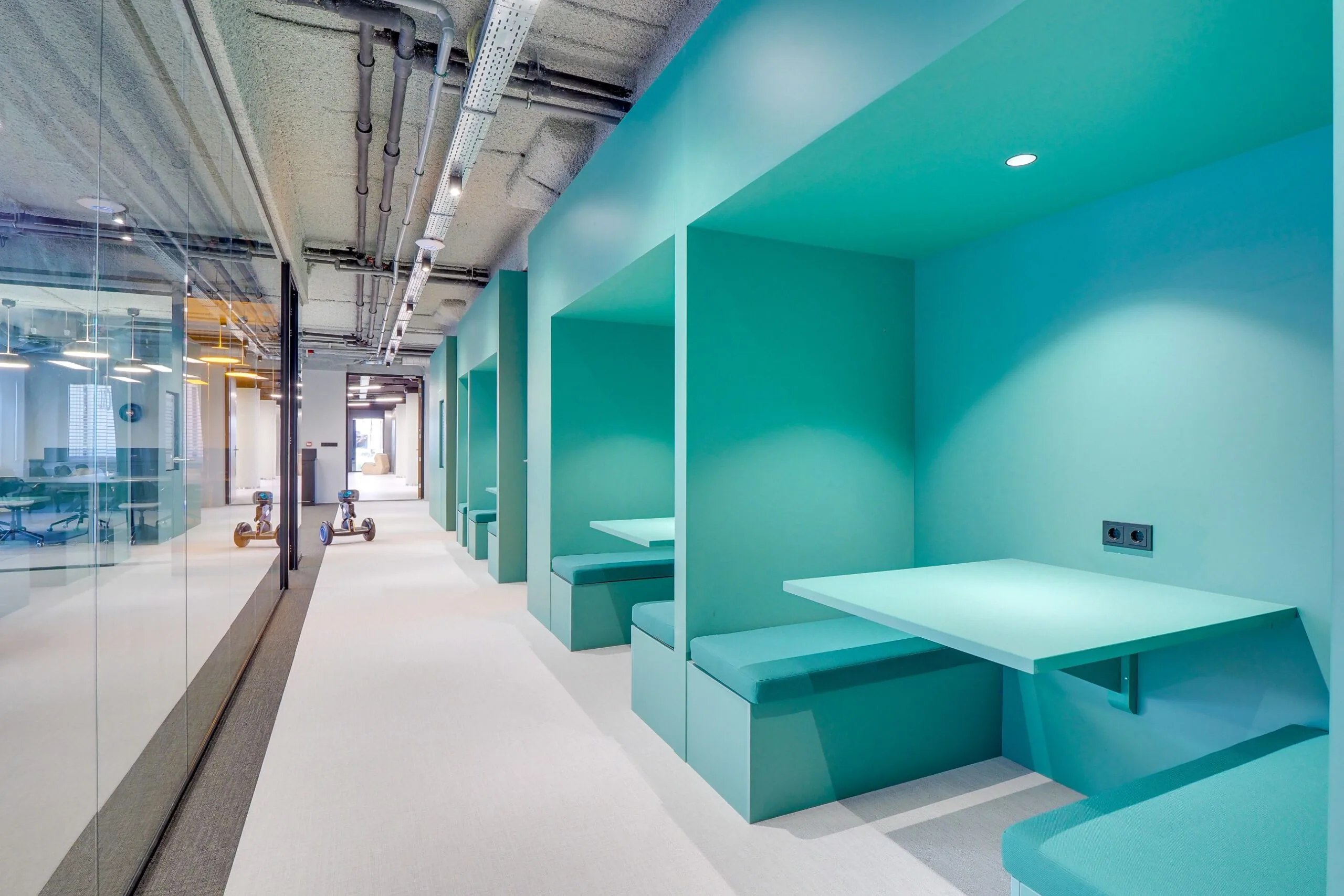 Moderne werkruimte aan de Europalaan 400 met turquoise zitnissen en glazen vergaderruimte.
