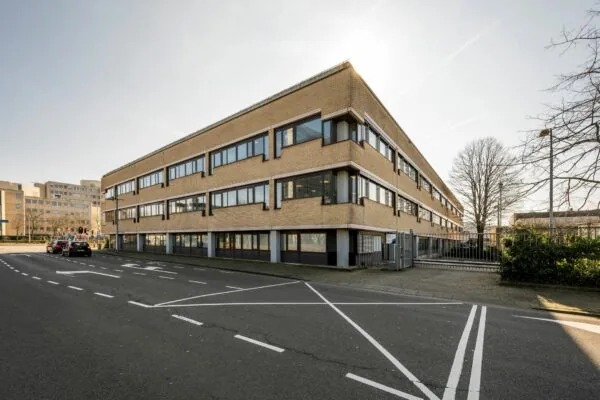 Hoekaanzicht van een modern kantoorpand aan de Europalaan 93 met beige bakstenen en grote ramen.