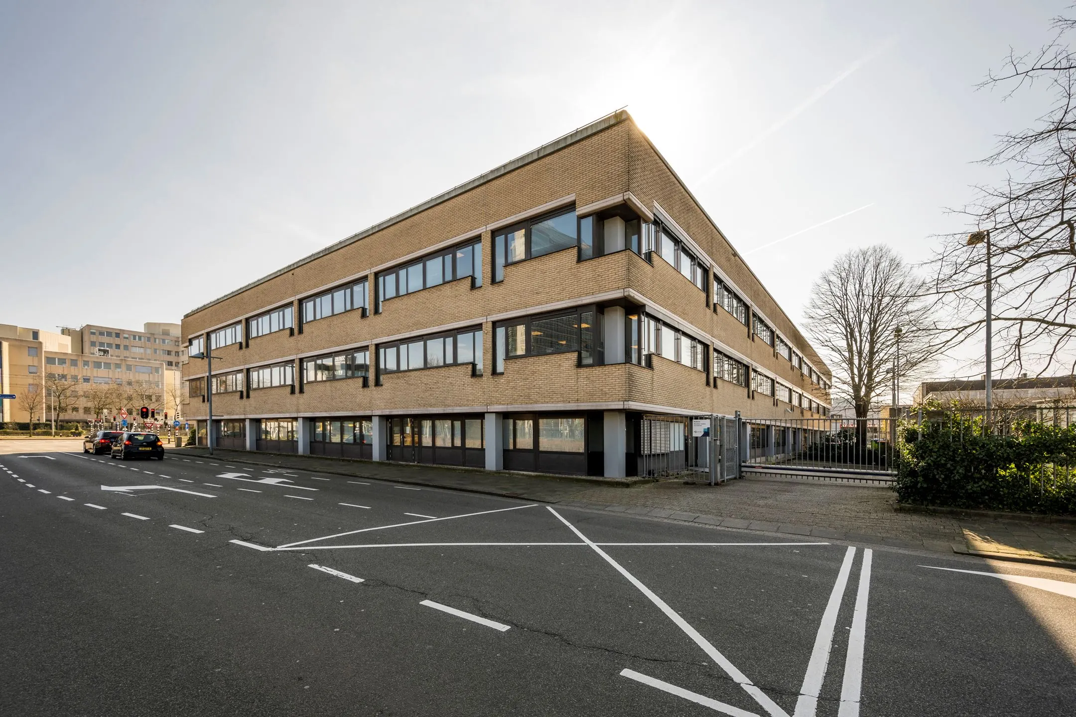 Hoekaanzicht van een modern kantoorpand aan de Europalaan 93 met beige bakstenen en grote ramen.