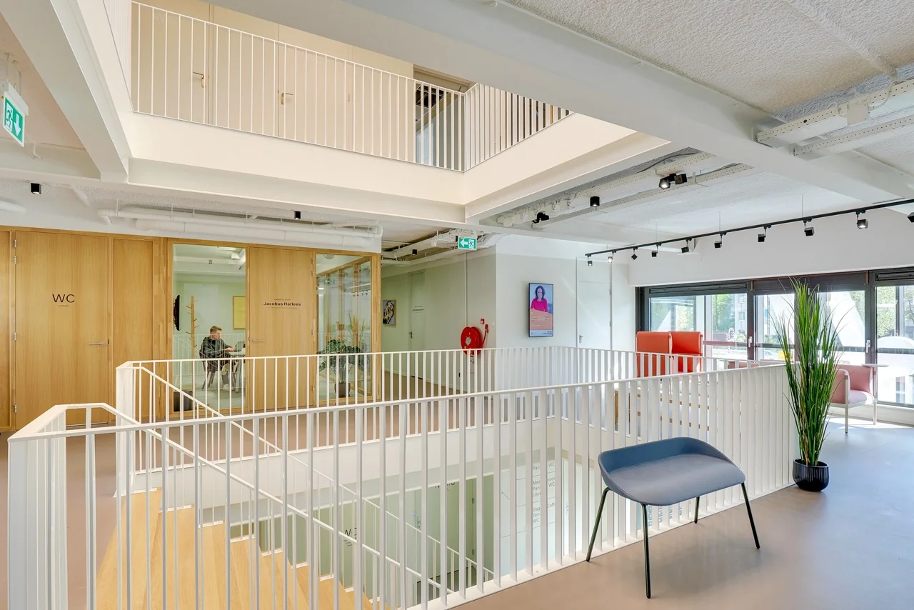 Moderne kantoorruimte aan de Europalaan 93 met open trapgat, houten deuren en lichtinval via grote ramen.