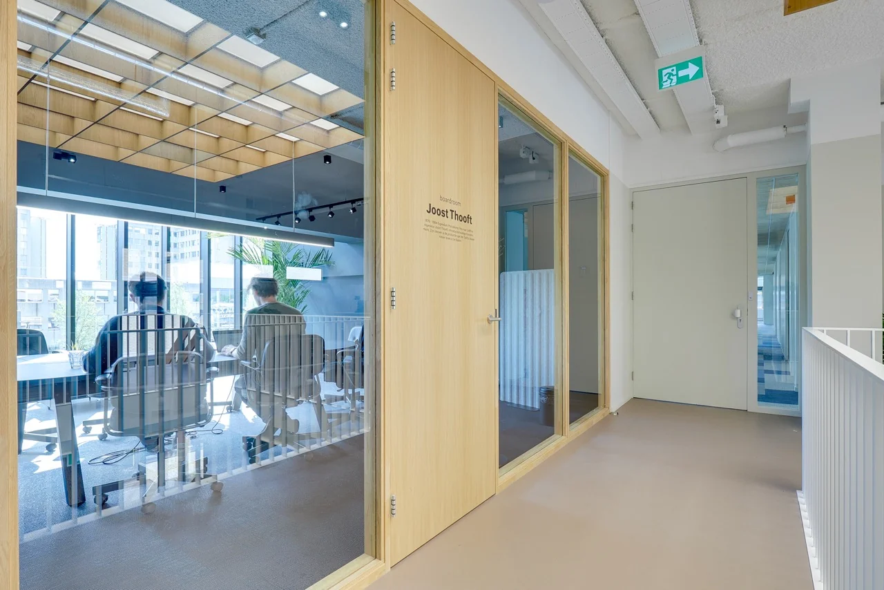 Vergaderruimte Joost Thooft met glazen wanden waarin mensen aan een tafel zitten in een modern kantoorgebouw aan de Europalaan 93.