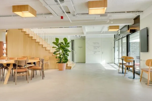Moderne en lichte kantoorruimte aan de Europalaan 93 met houten trap, ronde vergadertafel, planten en zitplekken langs de glazen wand.