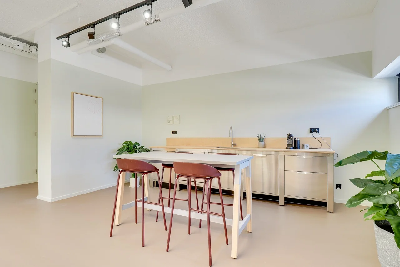 Moderne kitchenette met hoog tafelblad en drie barkrukken in een strak vormgegeven ruimte aan de Europalaan 93.