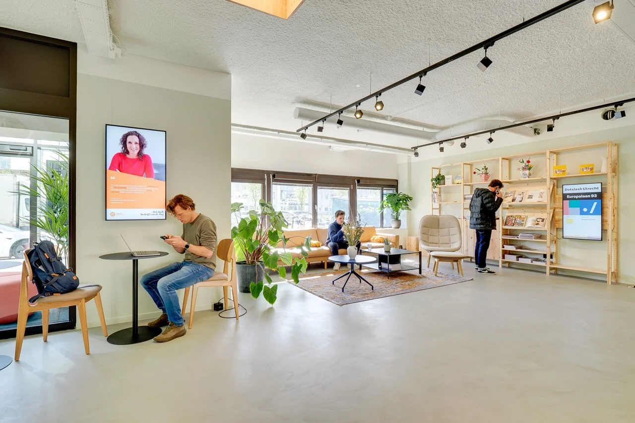 Moderne wachtruimte van DotSlash Utrecht aan de Europalaan 93 met zitplekken, planten, tijdschriftenrek en informatieschermen.