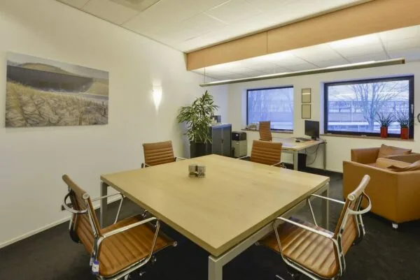 Moderne kantoorruimte in FlexOffiZ Amersfoort met vergadertafel, bureaus en leren stoelen.