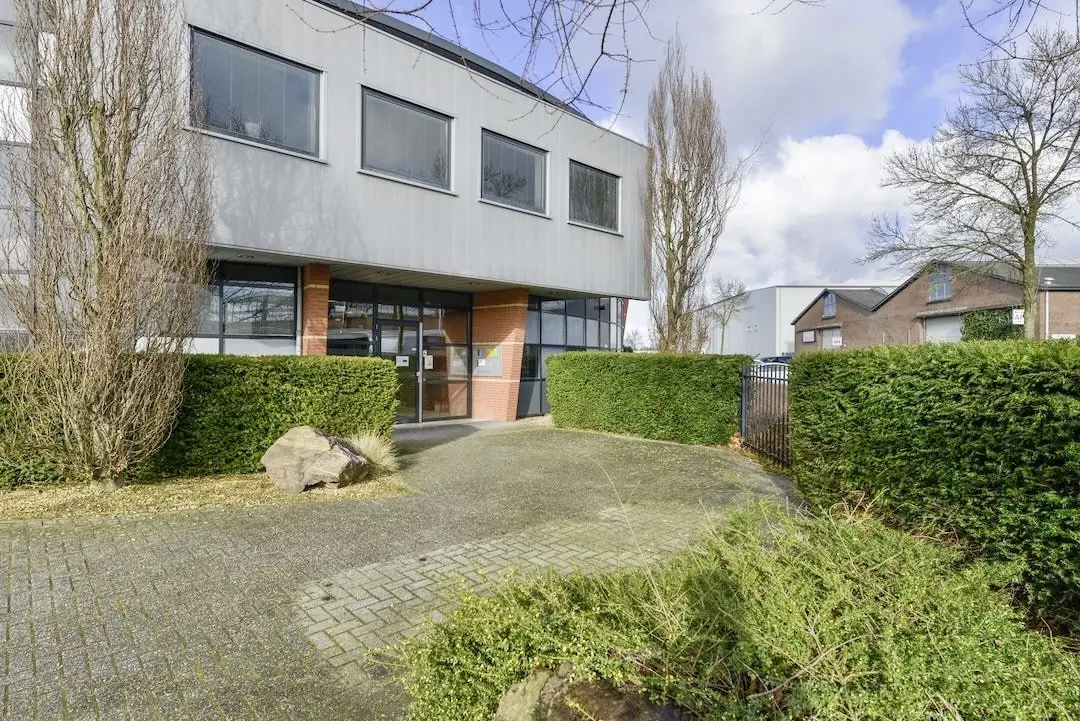 Vooraanzicht van het kantoorpand FlexOffiZ aan de Heliumweg 19 in Amersfoort, omringd door groen en bestrating.
