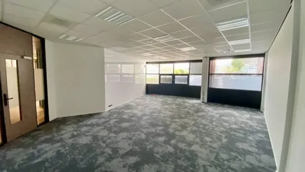 Lichte, lege kantoorruimte met tapijtvloer en grote ramen bij FlexOffiZ Amersfoort aan de Heliumweg 21.