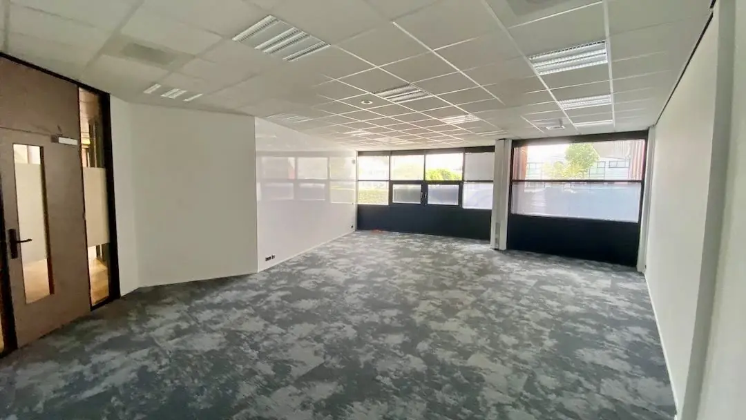 Lichte, lege kantoorruimte met tapijtvloer en grote ramen bij FlexOffiZ Amersfoort aan de Heliumweg 21.