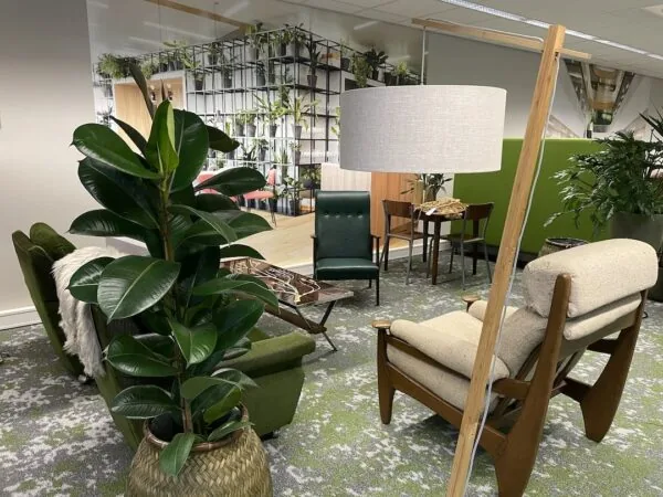 Moderne loungehoek bij FlexOffiZ Amersfoort met groene en houten meubels, planten en een grote vloerlamp.