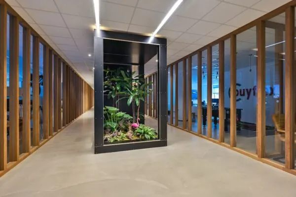 Moderne kantoorhal van FlexOffiZ Baarn met centraal een glazen plantenbak met tropisch groen en een roze flamingo.