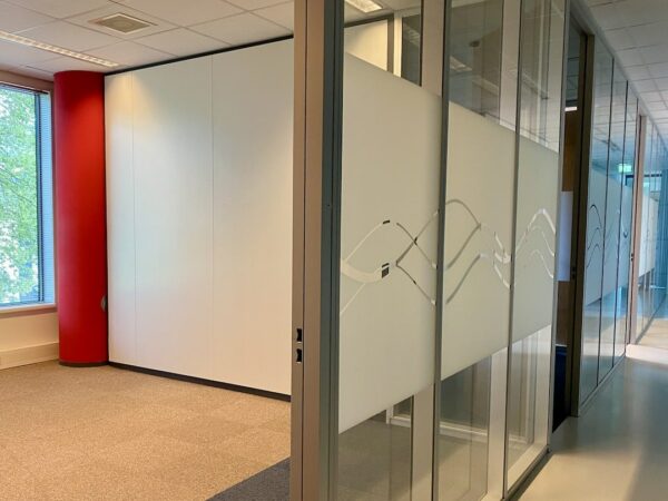 Moderne kantoorruimte bij FlexOffiZ Baarn met glazen wanden en een rood accent bij het raam.