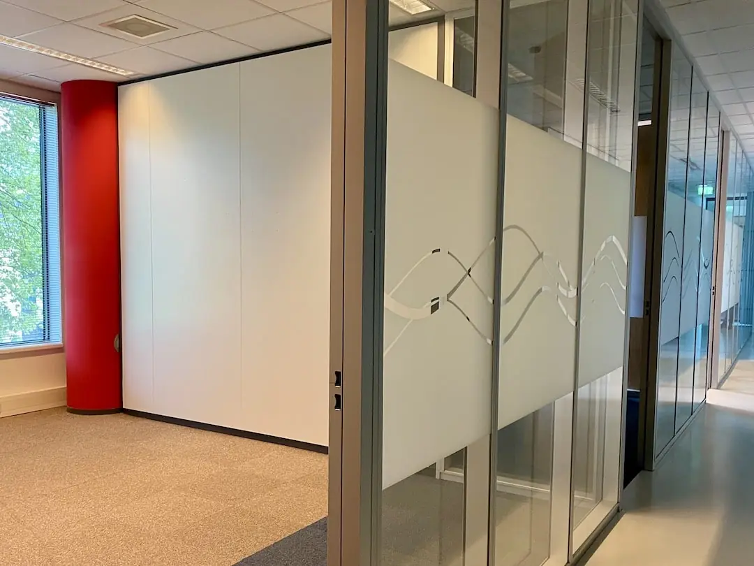 Moderne kantoorhal van FlexOffiZ Baarn met centraal een glazen plantenbak met tropisch groen en een roze flamingo.