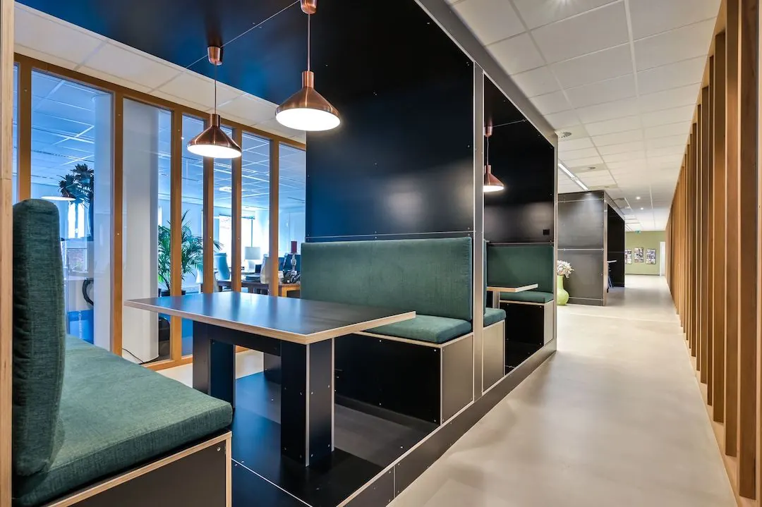 Moderne kantoorruimte in FlexOffiZ Baarn met ingebouwde zithoeken en hanglampen langs een glazen wand.