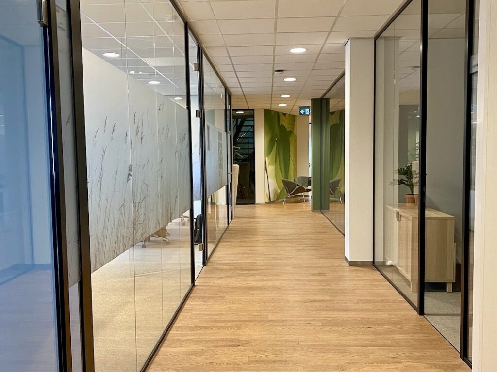 Moderne kantoorruimte bij FlexOffiZ Bodegraven met glazen vergaderruimtes en houten vloer.