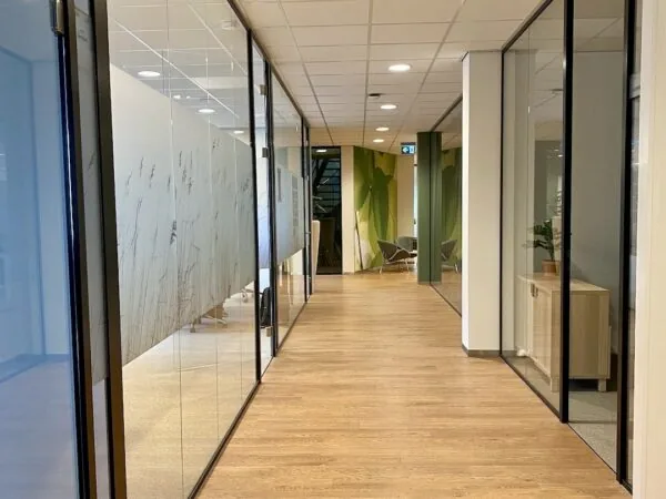 Moderne kantoorruimte bij FlexOffiZ Bodegraven met glazen vergaderruimtes en houten vloer.