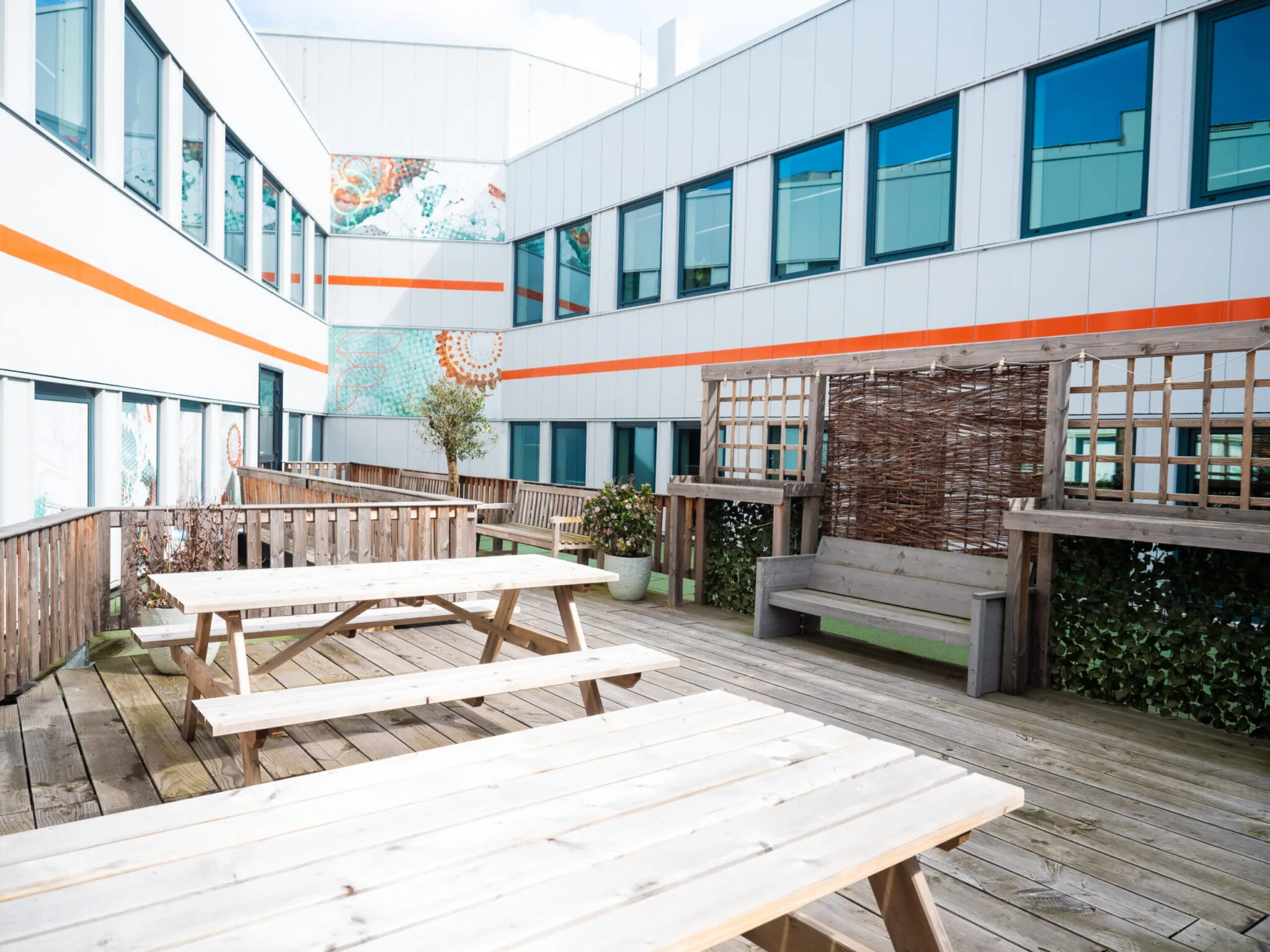 Houten dakterras bij Flexizone met picknicktafels, bankjes en omringd door een modern kantoorgebouw.