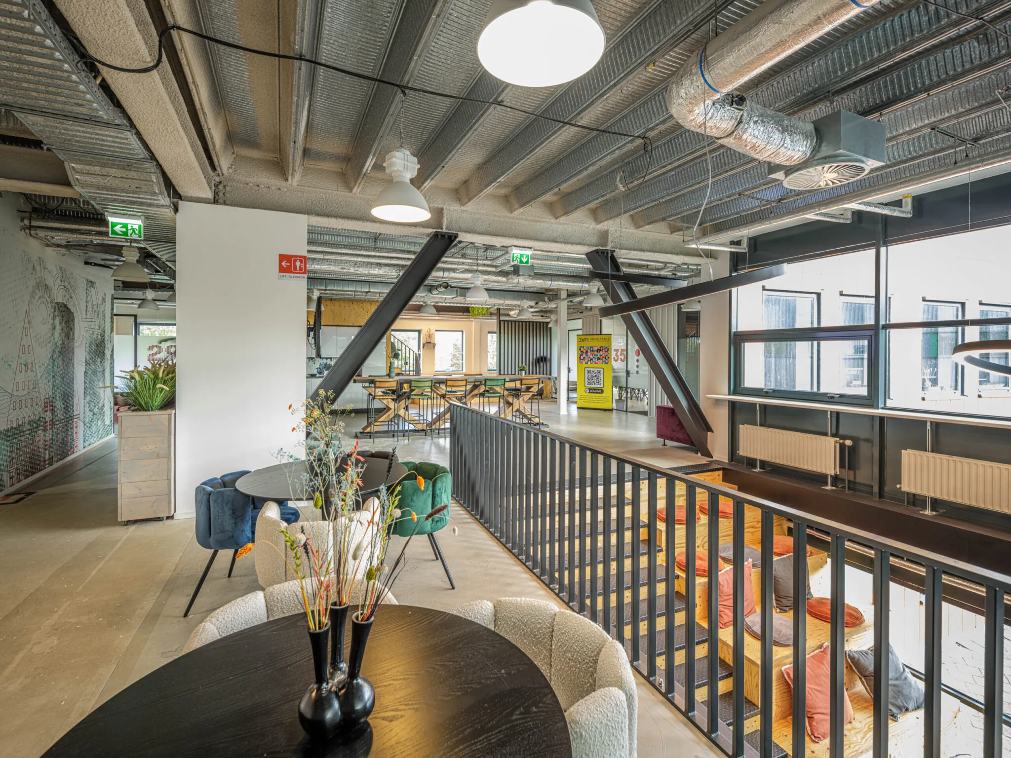 Moderne en kleurrijke coworkingruimte bij Flexizone 11 met zitplekken, planten en industriële afwerking.