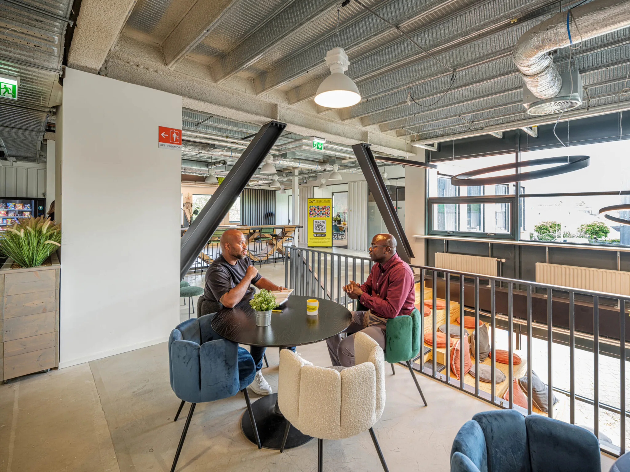 Twee mannen zitten aan een ronde tafel in een modern ingerichte ruimte binnen Flexizone 14.