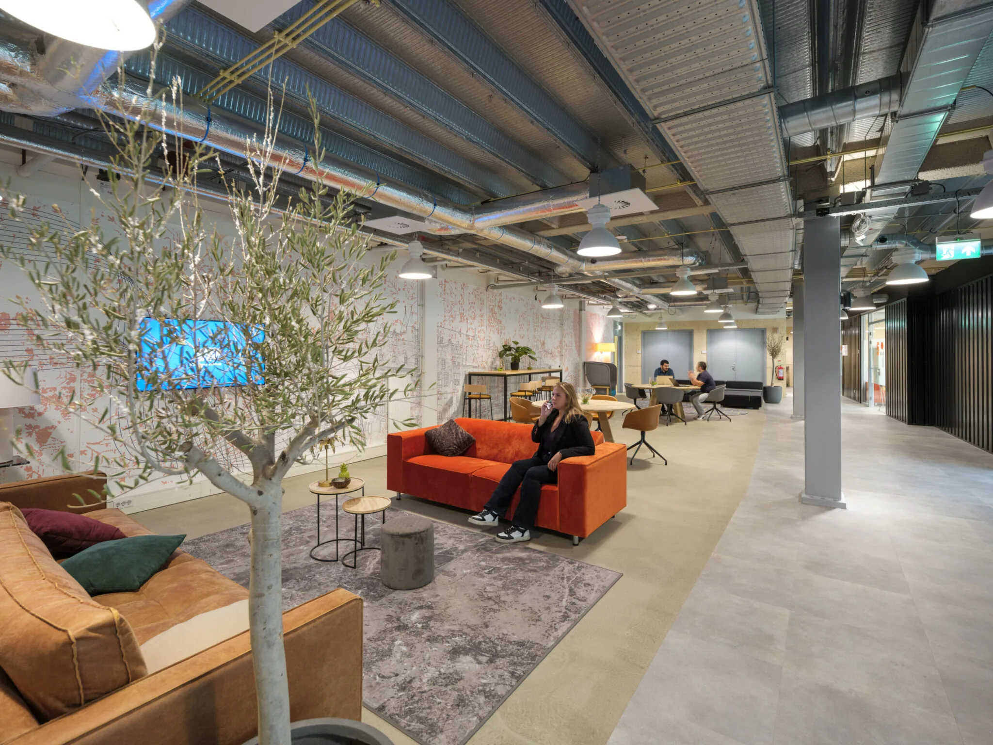 Moderne, open Flexizone-kantoorruimte met zithoeken, werkplekken en industriële plafondafwerking.