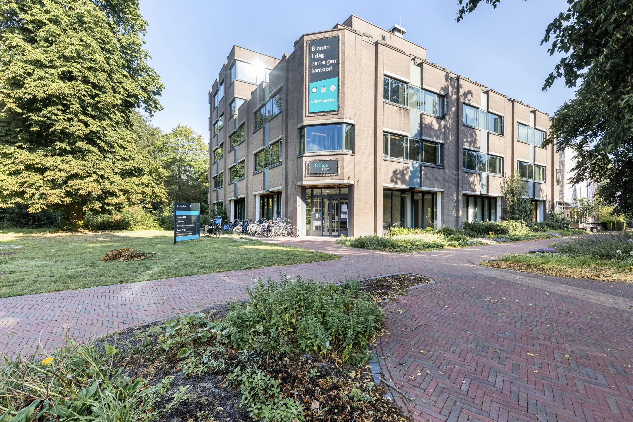 Modern kantoorgebouw aan de Fonteinlaan 5 in Haarlem, omgeven door groen en een bakstenen wandelpad.