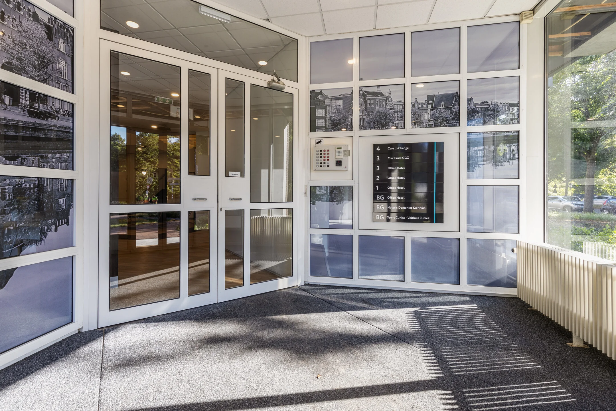 Entreehal van kantoorgebouw aan de Fonteinlaan 5 in Haarlem met glazen draaideur, intercom en bedrijfsnamenbord.