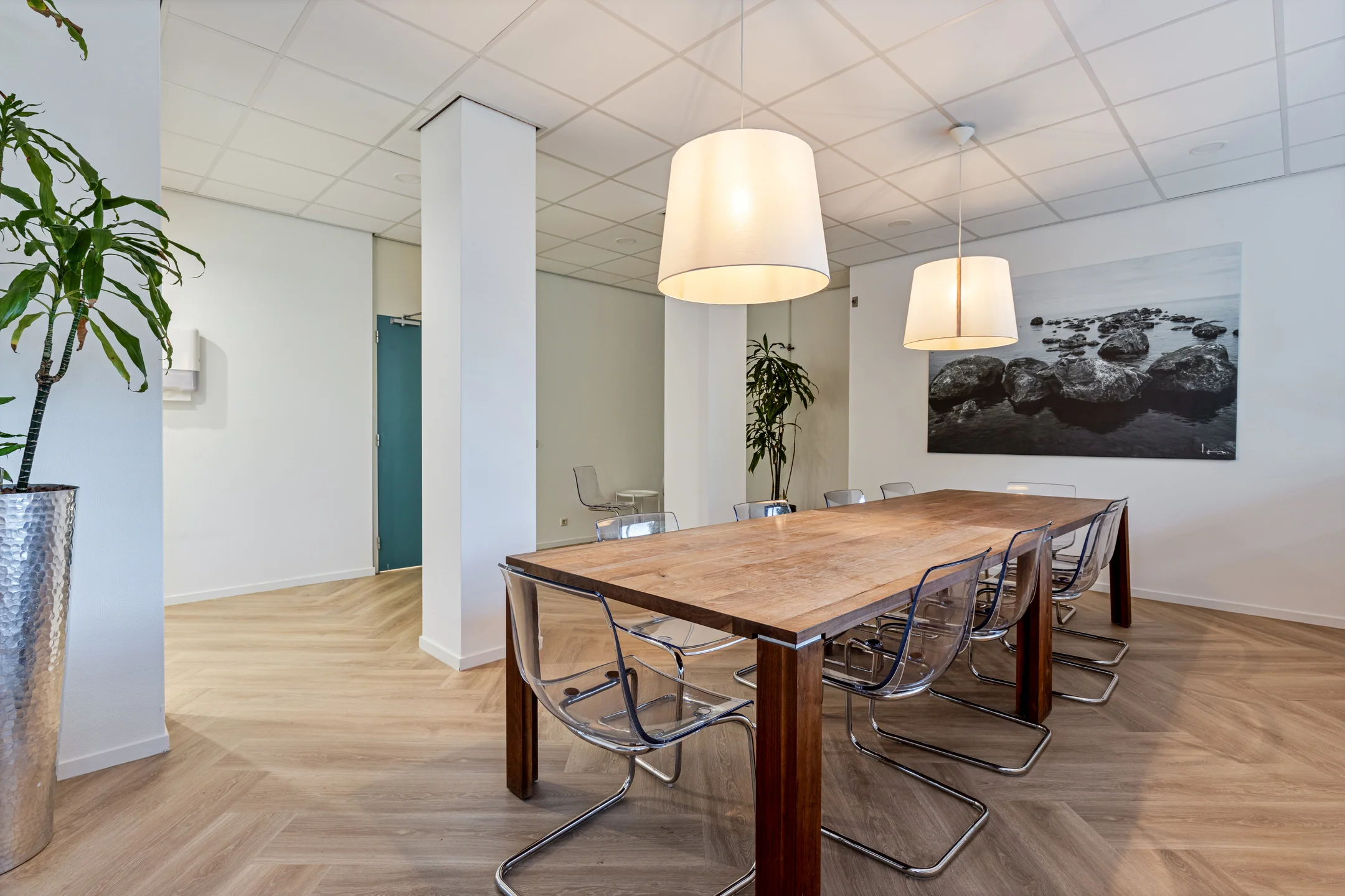 Moderne vergaderruimte aan de Fonteinlaan 5 in Haarlem met houten tafel, doorzichtige stoelen en sfeervolle verlichting.