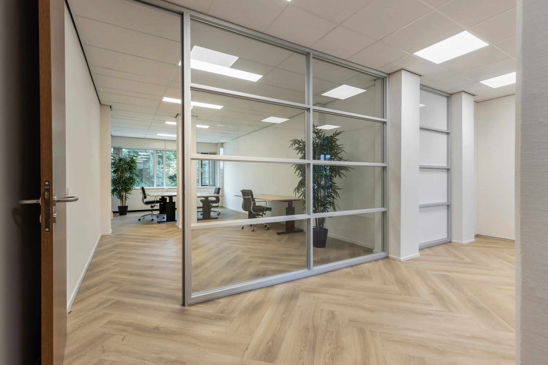 Modern kantoorinterieur aan de Fonteinlaan 5 in Haarlem met glazen vergaderruimte en houten visgraatvloer.