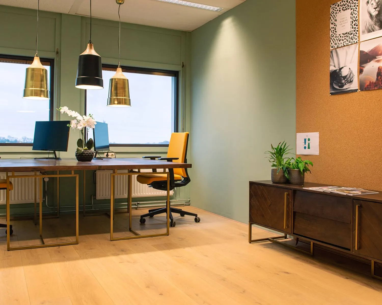 Modern kantoorinterieur met twee bureaus, gele bureaustoelen, hanglampen en groene accenten.